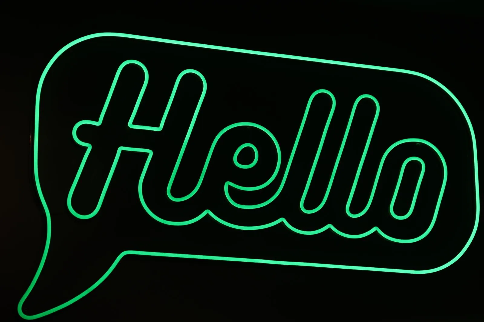 Bright green neon sign displaying 'Hello' in Catania, Sicily.